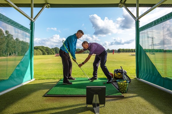 a golf lesson taking place at a driving range